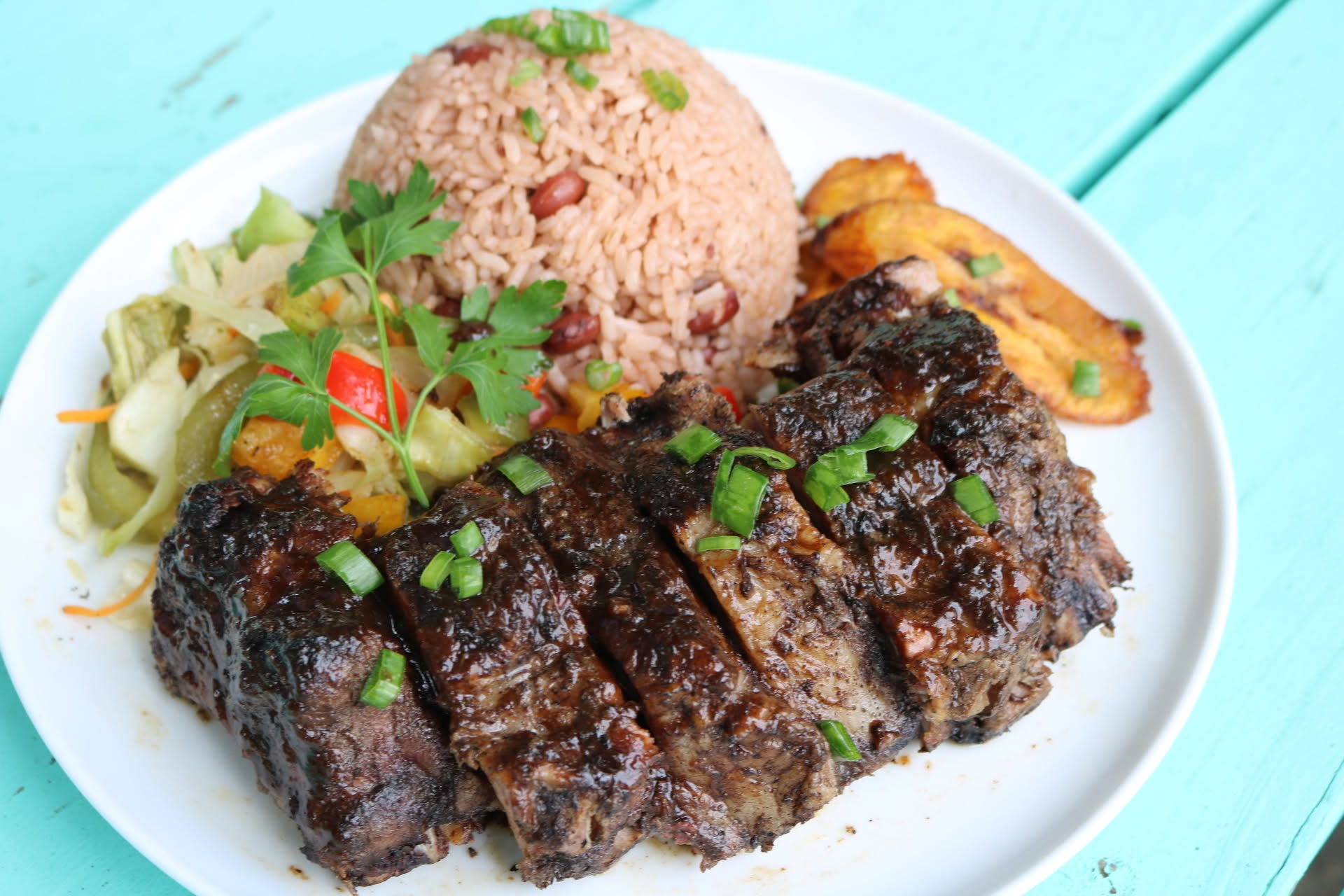 Jamaican plate with jerk steak, rice and peas, cabbage and fried plantain