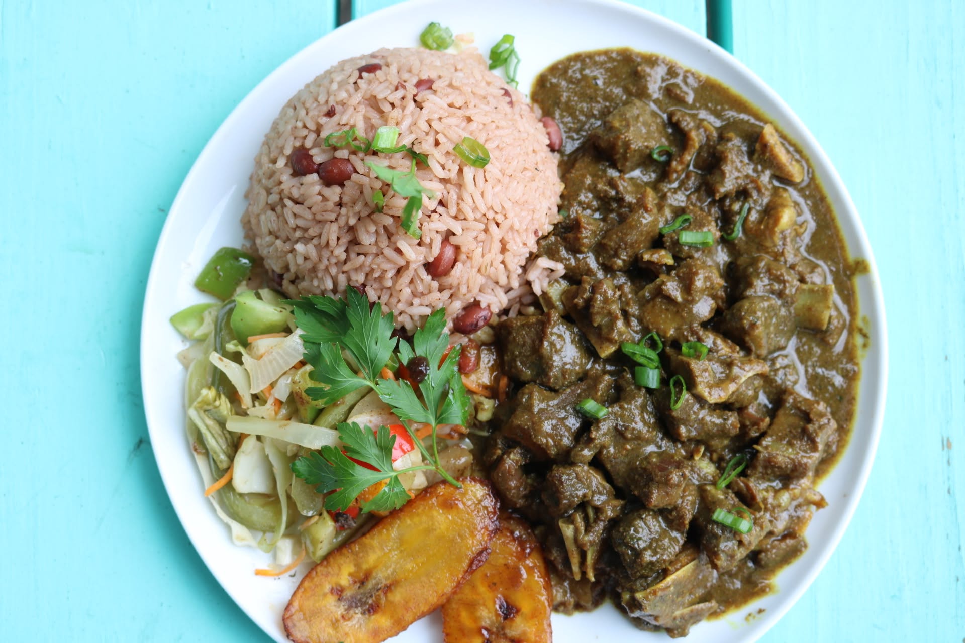 Jamaican curry plate with rice and peas, cabbage and fried plantain