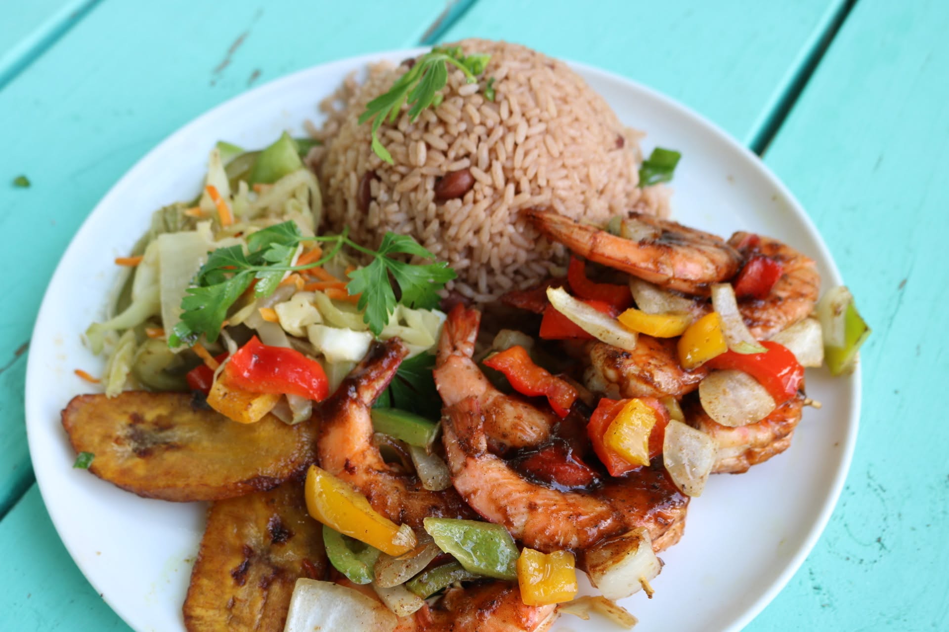 Jerk shrimp with peppers, rice and peas and fried plantain
