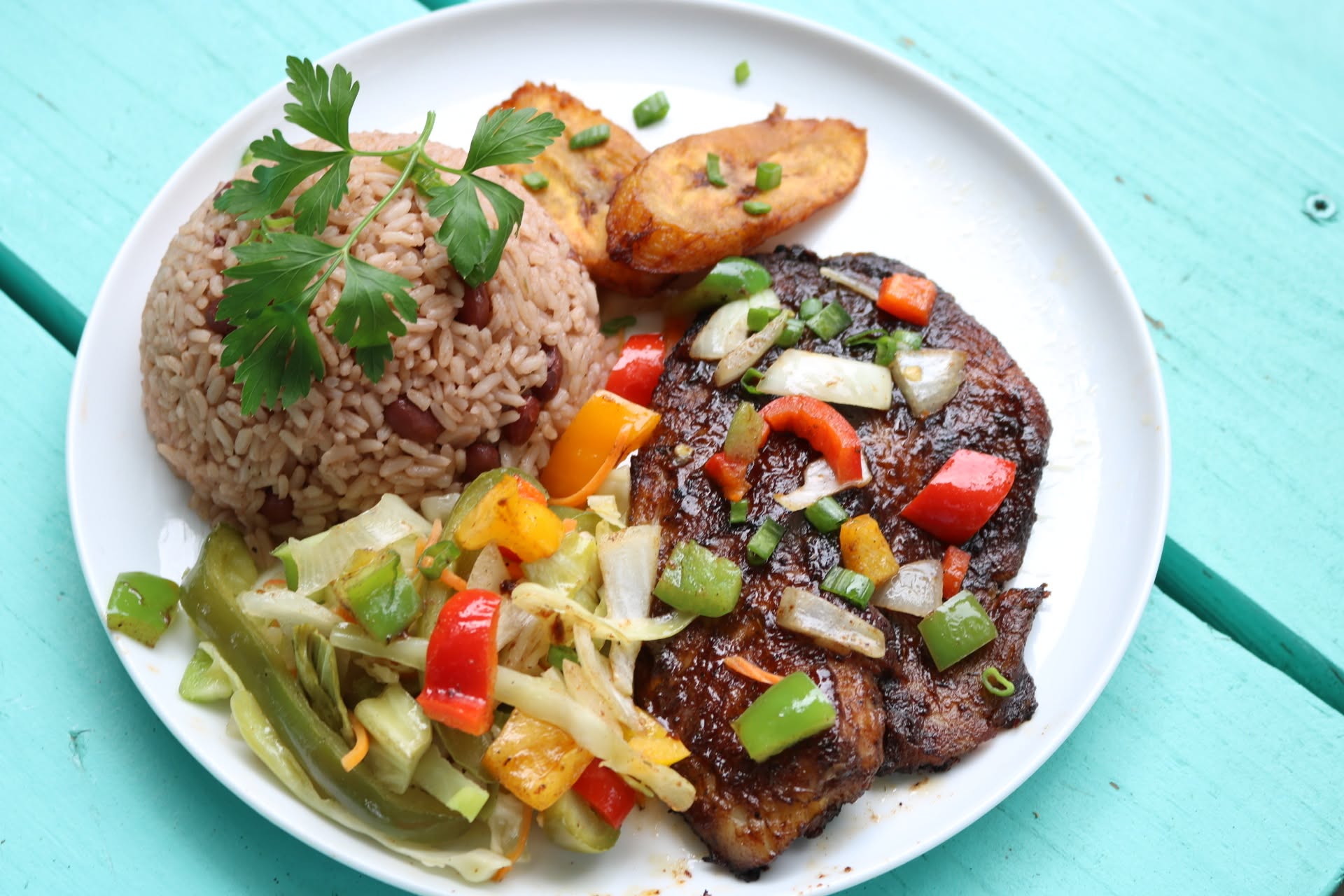 Jerk steak with peppers and onions over rice and peas