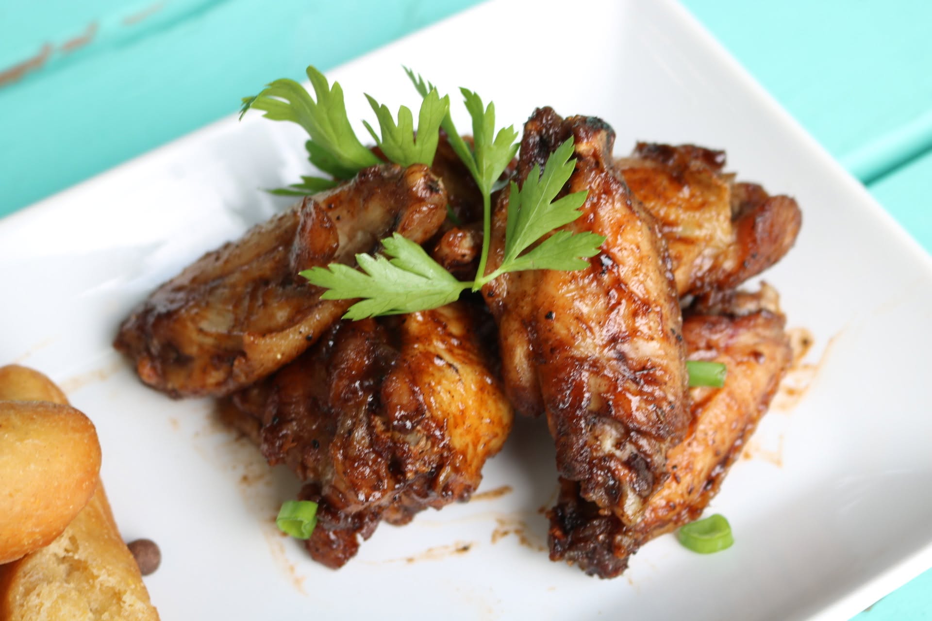 Jerk wings with fried plantain on a white plate